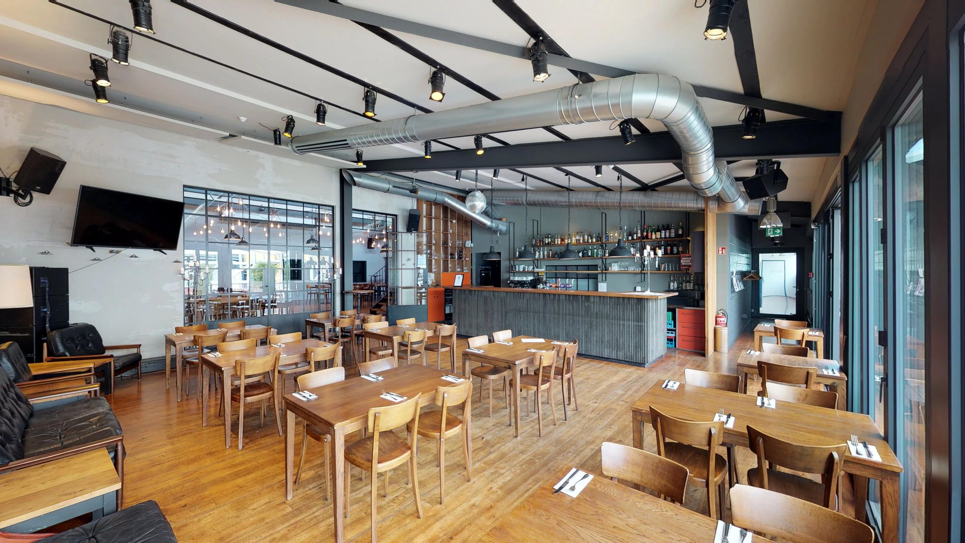 Der Saal im schmatz mit Industriedecke, Stahlträgern und offener Bar