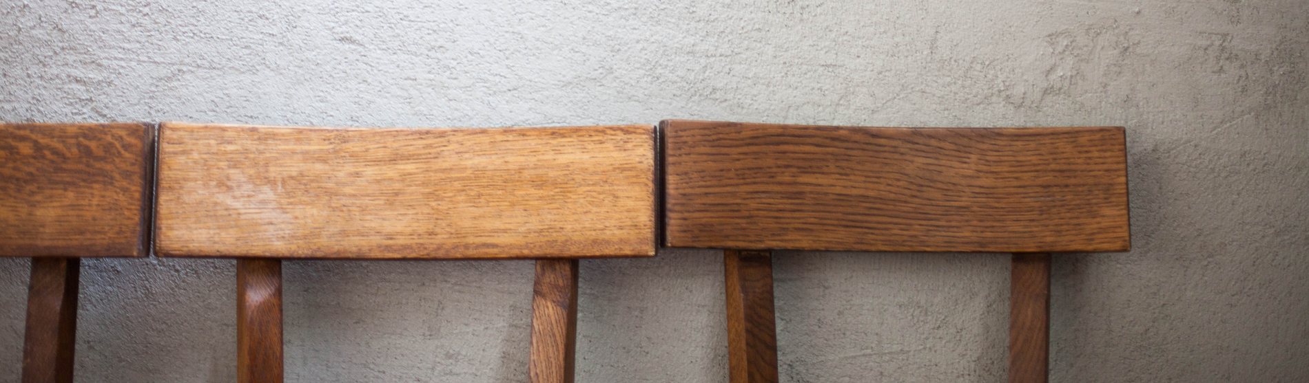 Holzstühle vor Betonwand