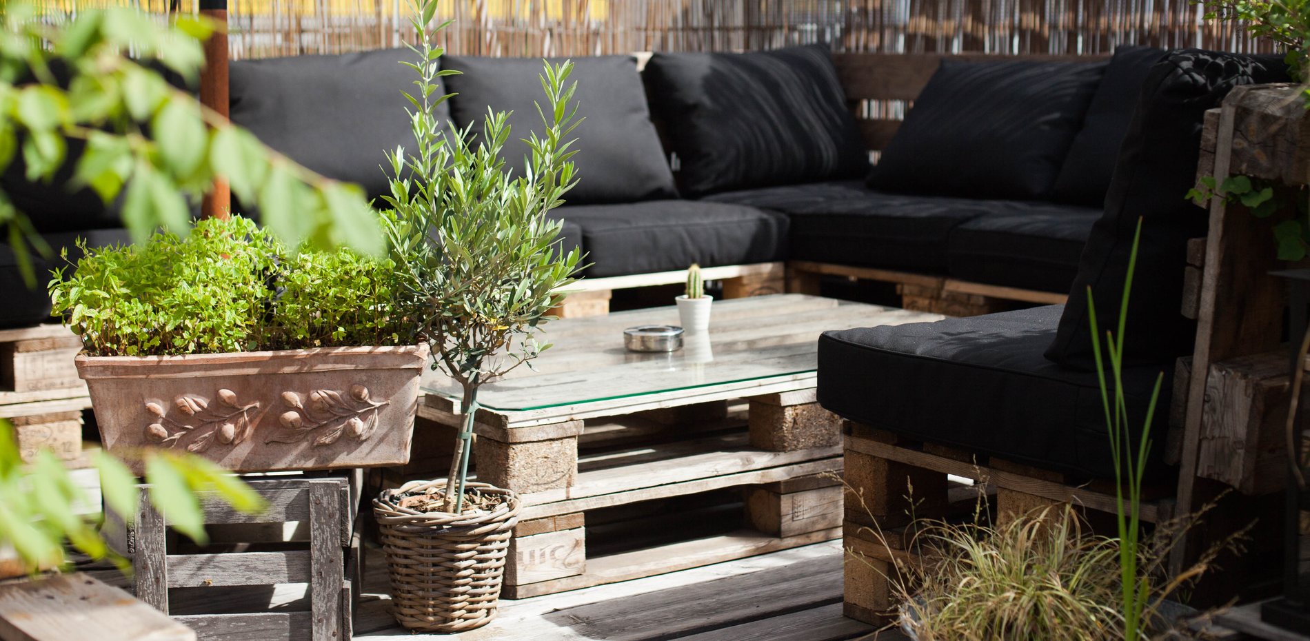 Dachterrasse im schmatz mit Palettenmöbeln und Olivenbaum